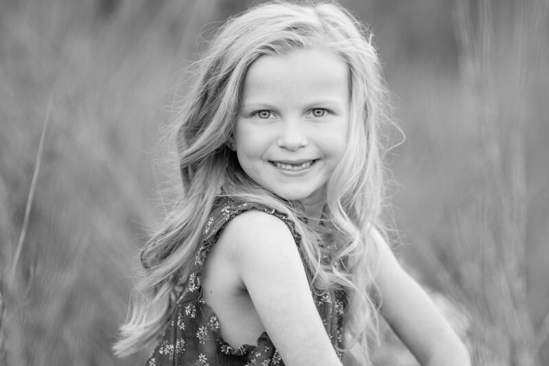 Little girl sitting in a field near the Boise Greenbelt.