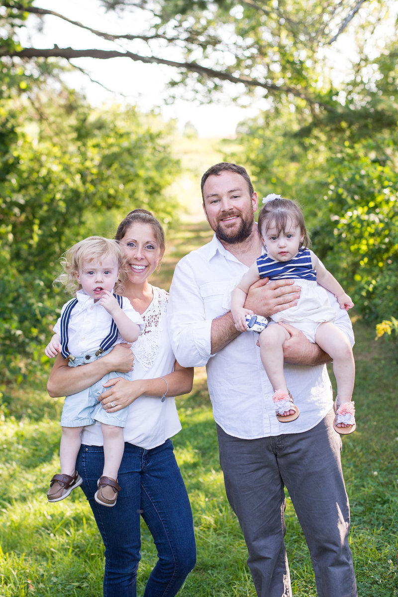 Mom and Dad holding young twins in field