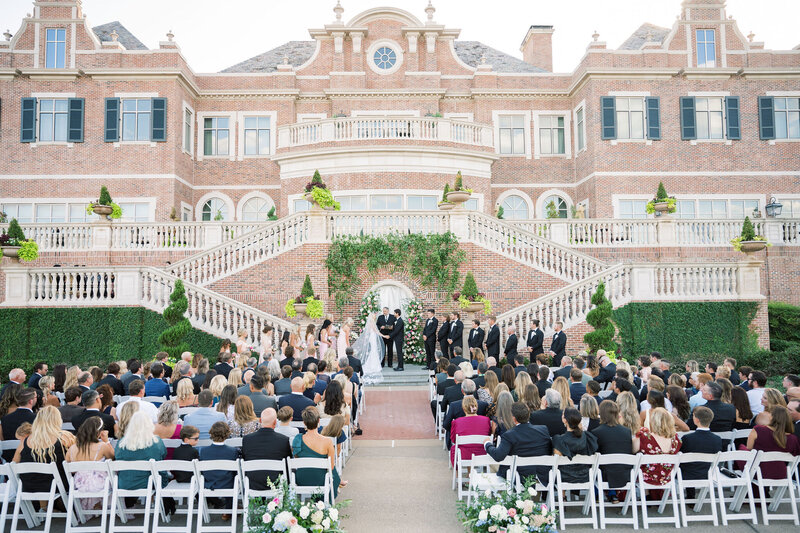 Bride and groom kissing with their reception and guests in the background