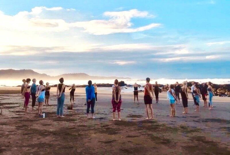 Yoga class in a circle formation on Playa Negra beach during yoga certification program in Costa Rica