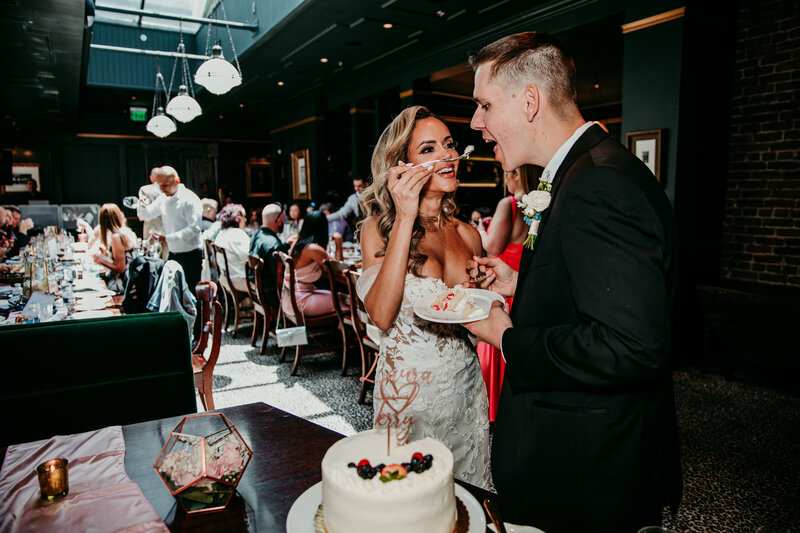 Bride and groom sharing cake during their San Francisco elopement celebration at a cozy indoor reception, captured by San Francisco elopement photographer Kristin Smith.