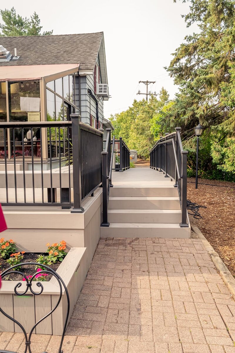 A low-maintenance deck with steps and ramp up to a local frozen yogurt shop. 