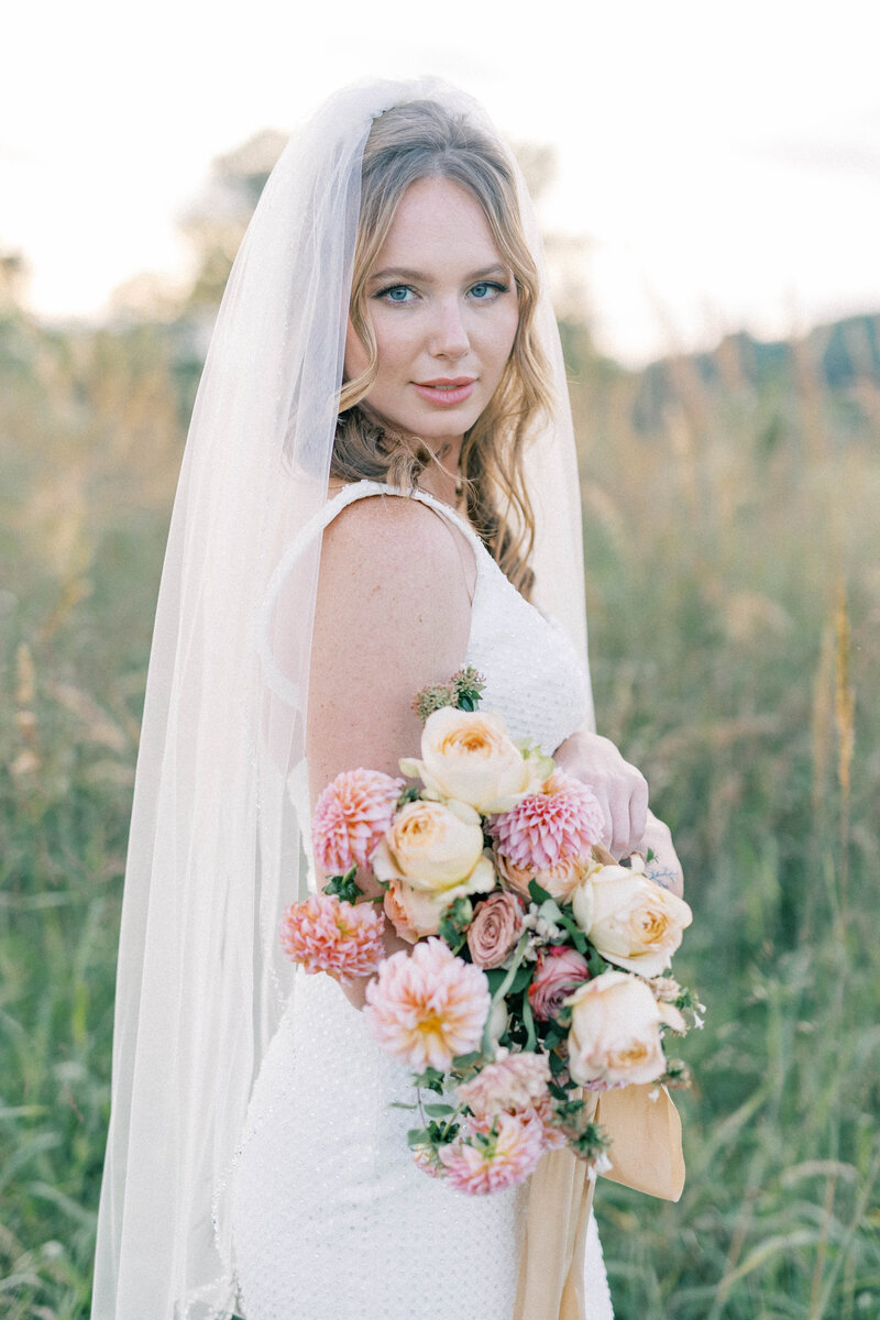Film Knoxville bride holding thistle and lace florals bouquet at marblegate farm in field