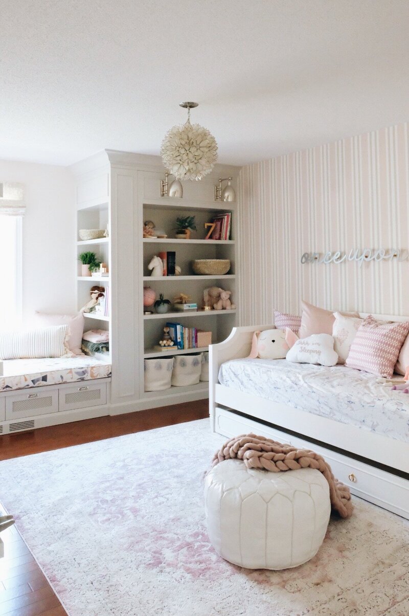 little girls playroom with striped wallpaper and built in bench with bookshelves