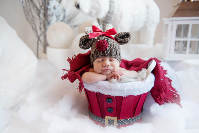 newborn baby boy in a Santa bucket with a reindeer hat for his newborn Christmas maternity photos 