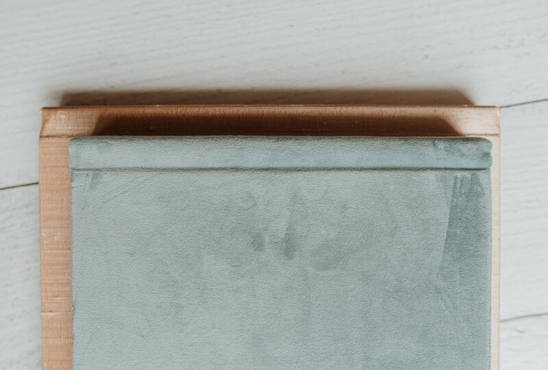 Two heirloom fine art photo albums lay on a wooden table 