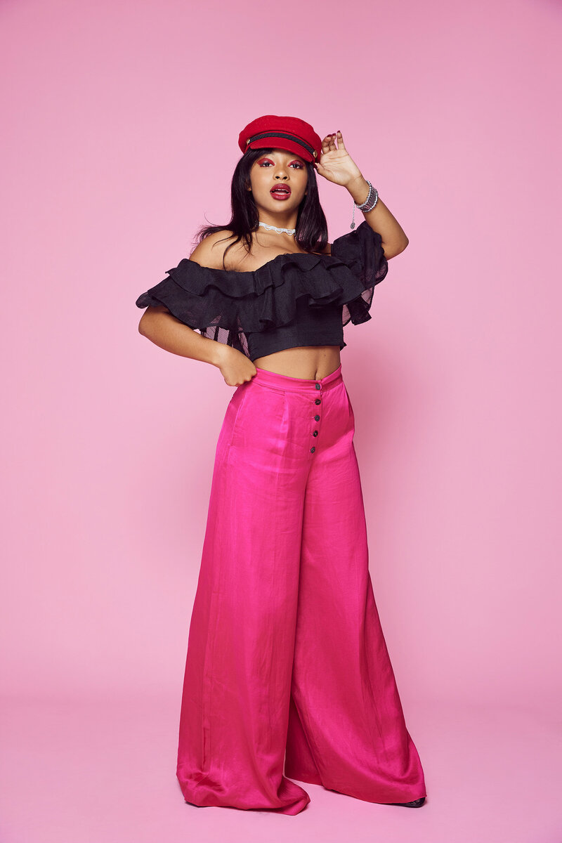 Studio fashion portraits of a teen girl wearing hot pink wide-leg pants and black ruffle crop top on pink background – Los Angeles senior photographer