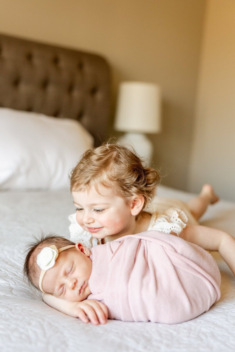 Oldest sibling smiling at baby, taken by minnesota newborn photographer Kacey Wyrick