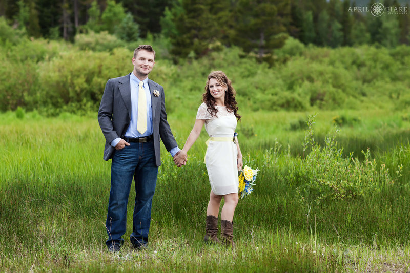 Couple holds hands in a pretty mountain meadow at Lily Lake in Estes Park