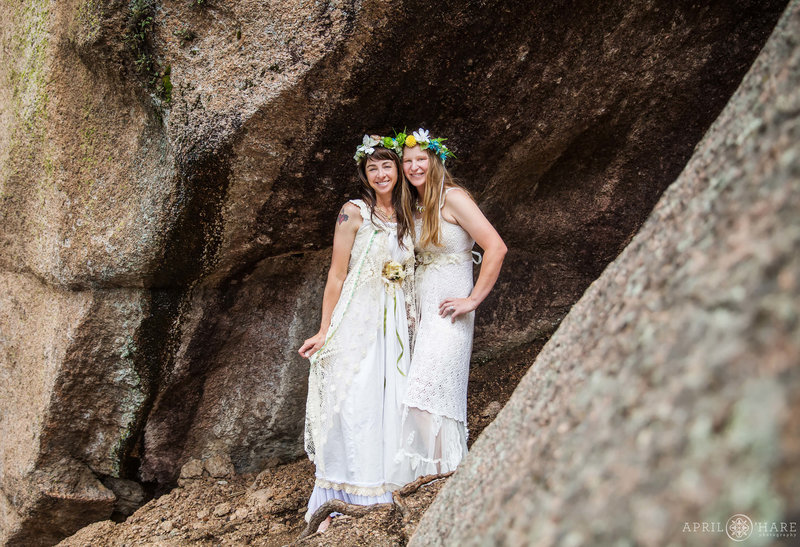 Two brides on their wedding day wear flower crowns in a rocky area of the Bucksnort Disc Golf course in Pine Colorado