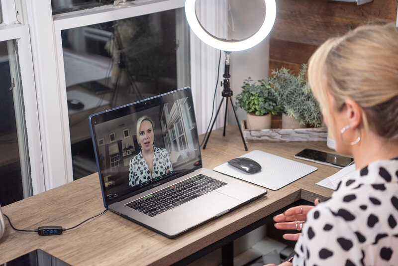 A woman sitting in front of her computer recording a public speaking webinar for her consulting firm.