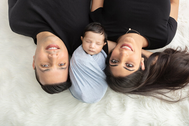 happy new family of three newborn baby portrait aerial view with baby boy sleeping between mommy and daddy