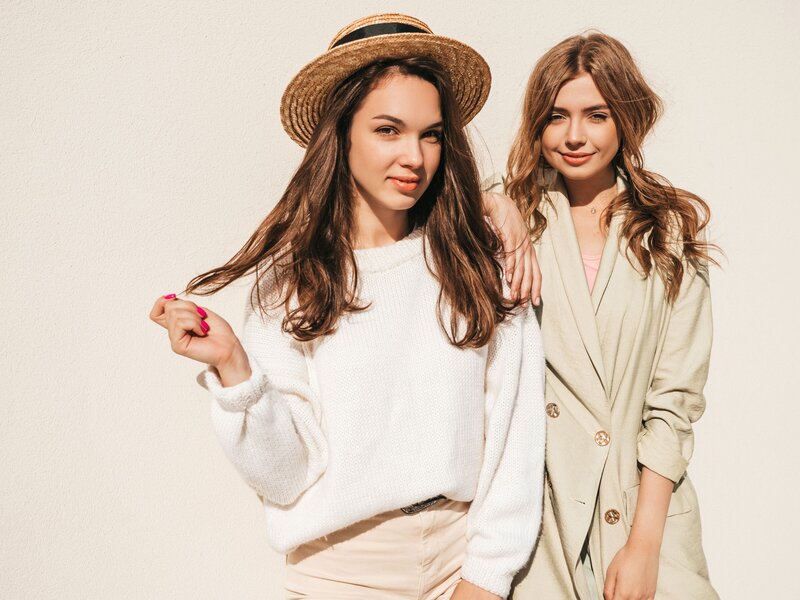 An image of two young women in their twenties wearing stylish finds found in delay beach, florida include a white oversized sweater, a bohemian hat, and a blazer.