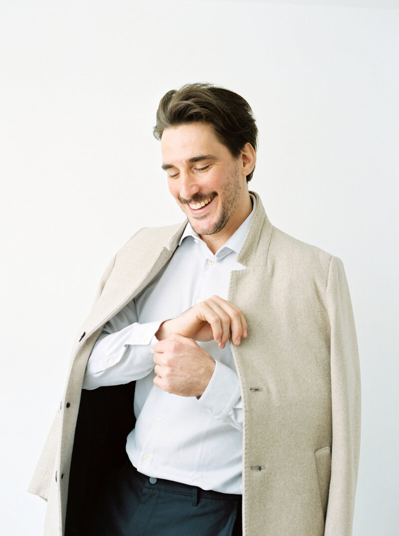 Man smiles while fixing the cuff of his shirt