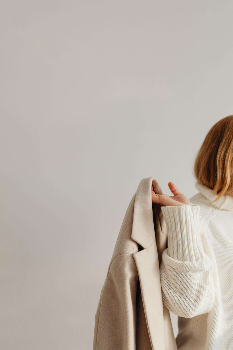 A person in a cozy white sweater holds jacket over shoulder, with text about how a strong brand grabs attention and builds relationships.