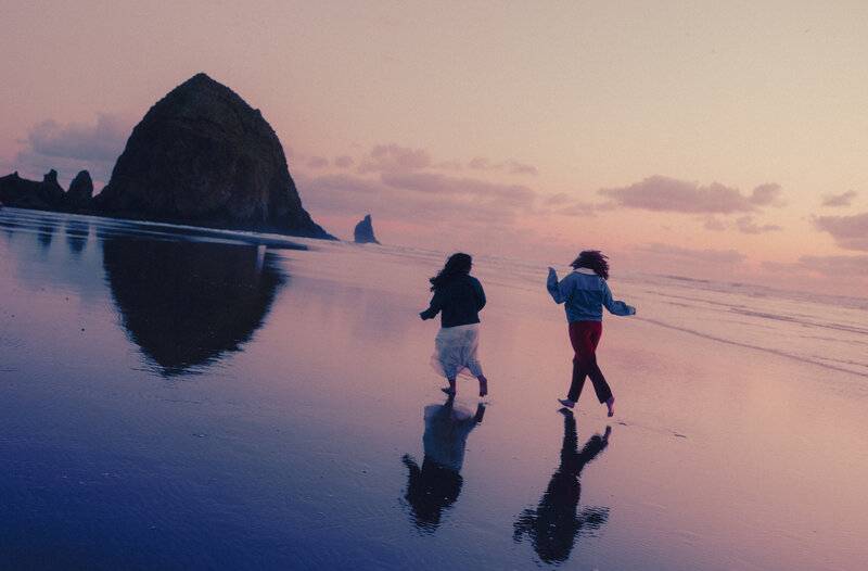 couple running torward haystack rock 