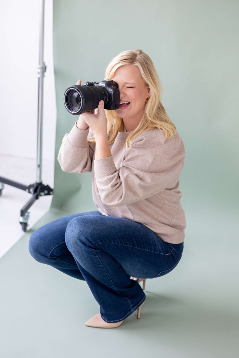 women in floral blue dress sitting on a piece of driftwood on the beach
