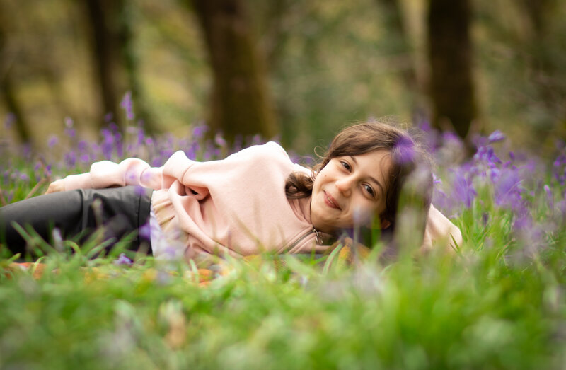 Girl lays smiling in the bluebells