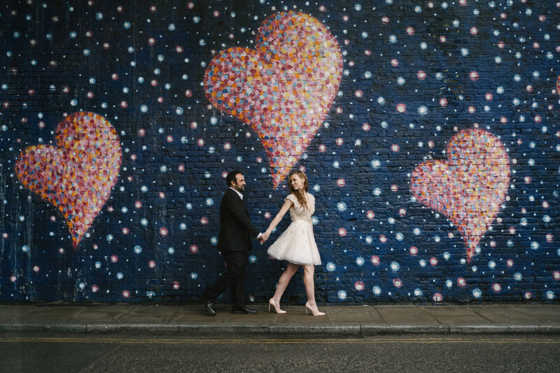 A bride and groom walking pass street art.