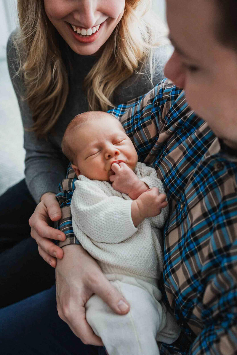 Joyful parents holding their newborn, encapsulating the warmth and love in Cleveland lifestyle newborn photography.