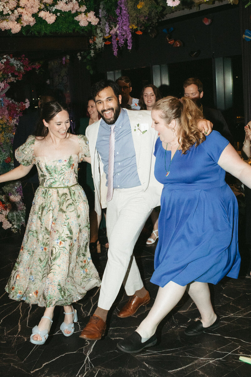 wedding guests dancing holding one another hopping and kicking their feet to the rhythm of the dabke dancers