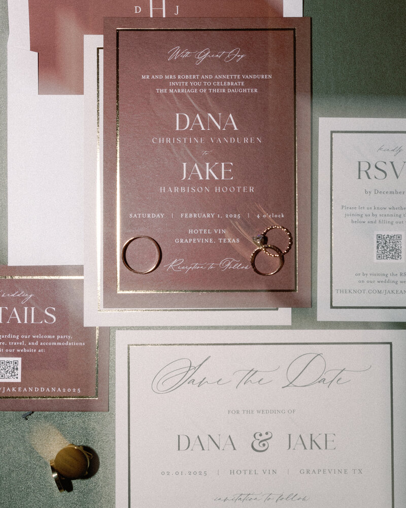 A beautifully styled wedding invitation suite for Dana & Jake, featuring modern typography, warm tones, and delicate wedding rings placed on top