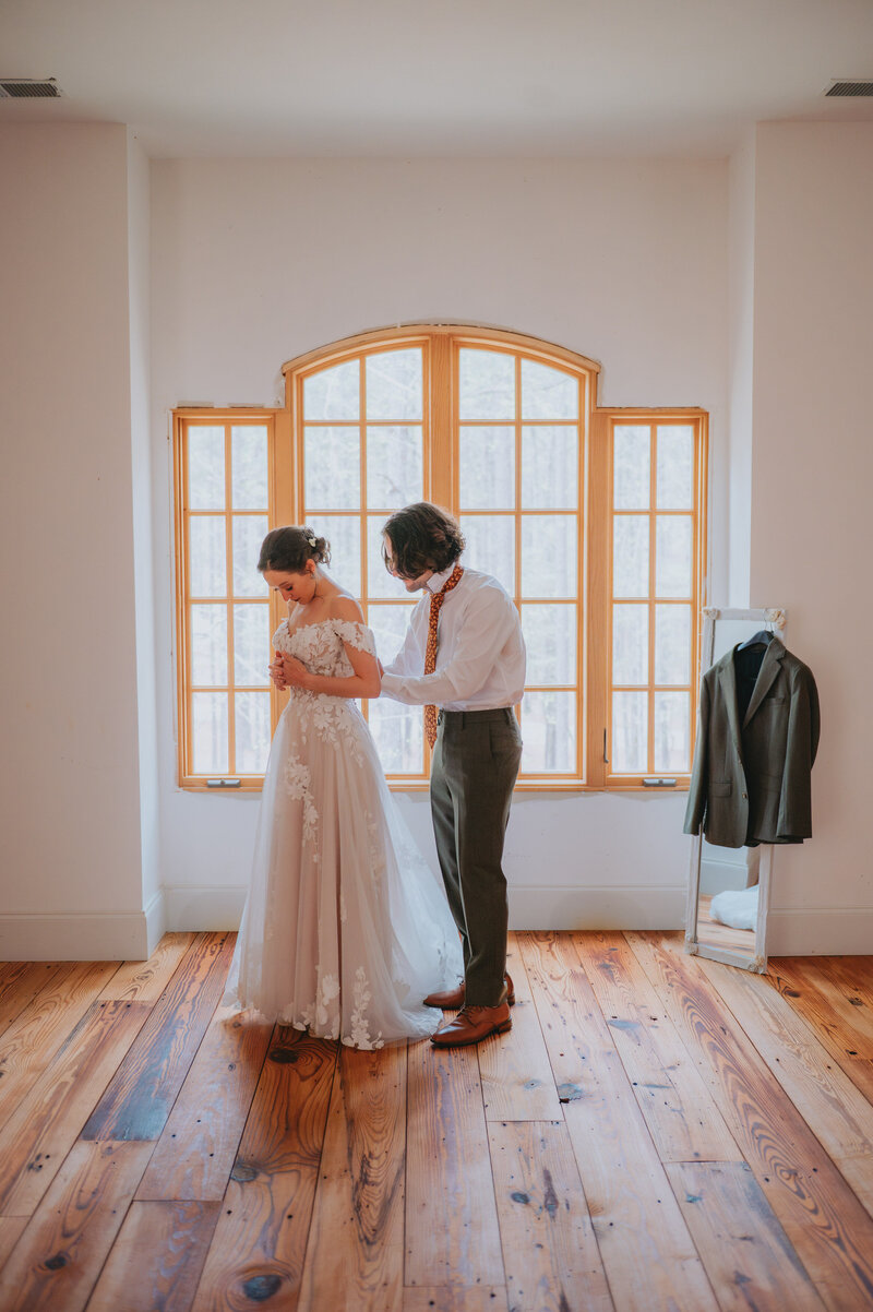 A couple helps one another get ready on their wedding day