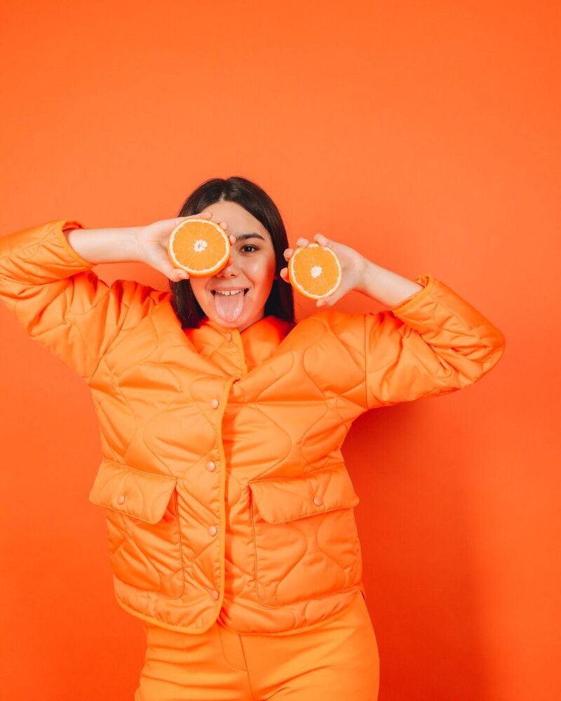 woman holding orange halves over her eye