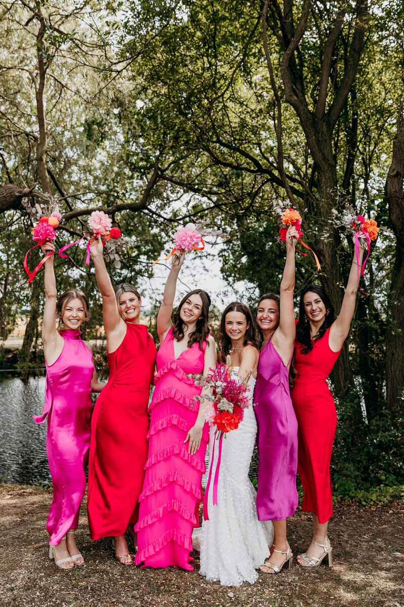 Bride and her bridesmaids wearing pink and red celebrating with flowers