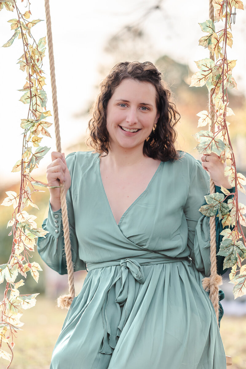 The photographer of Justine Renee Photography wears a mint colored dress and sits on a rope swing.
