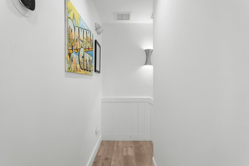 Hallway at the Surf House with nostalgic Panama City Beach artwork and modern wall sconce lighting.