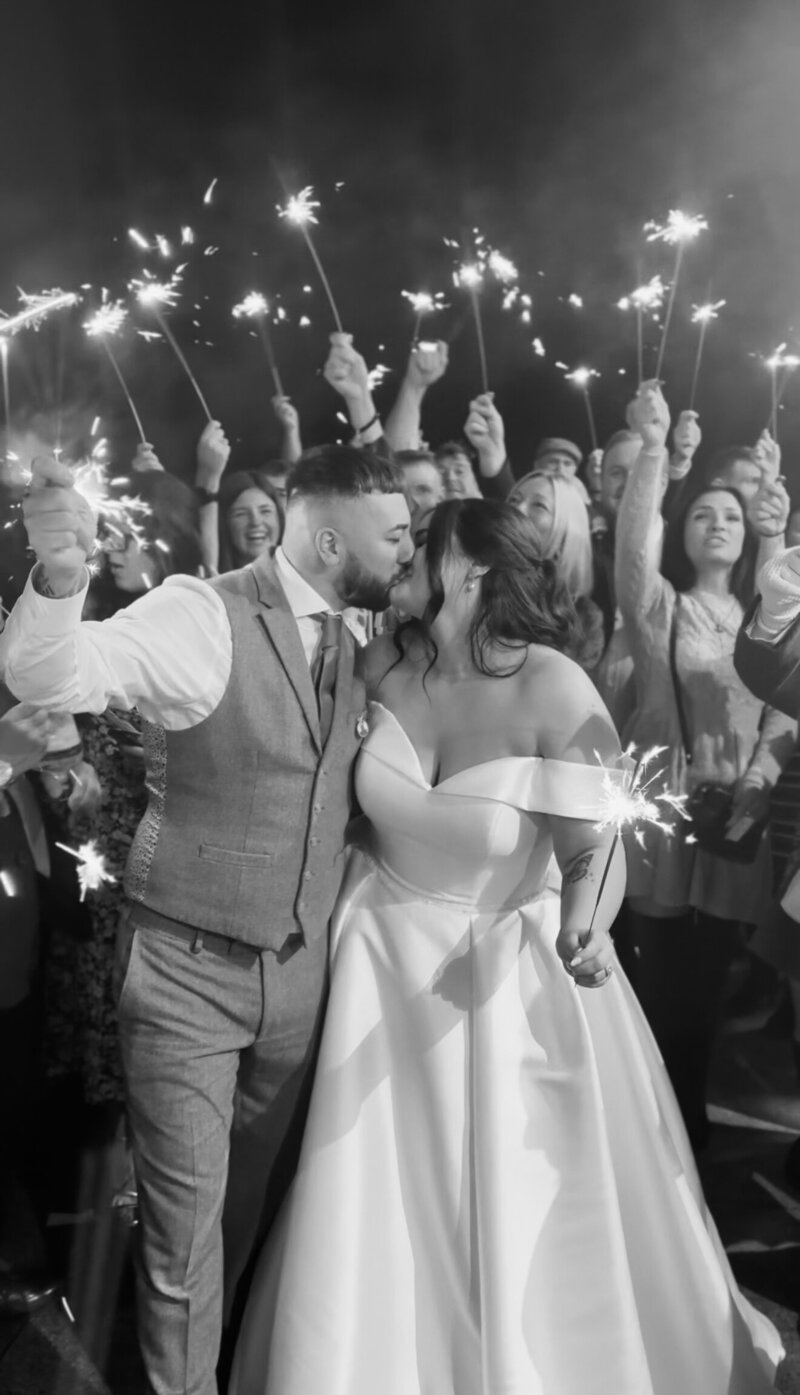 Bride and Groom kissing beautifully during a sparkler photo with their guests