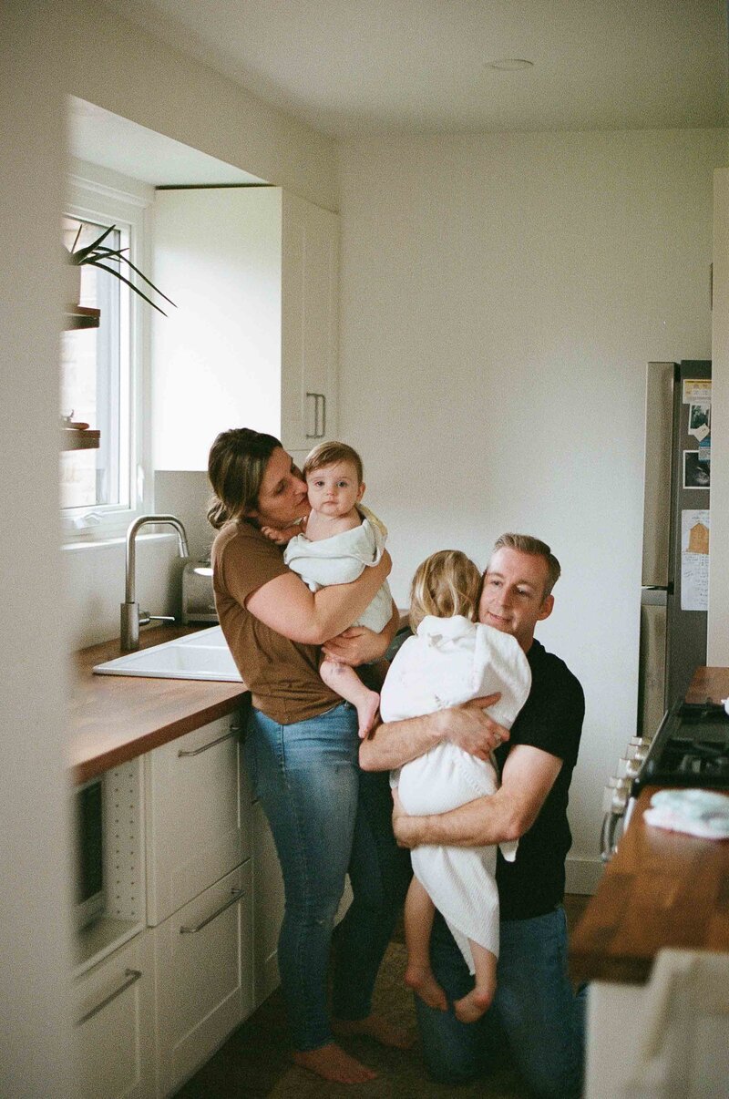 a mom and dad holding their children in towels after they have had a bath in the sink