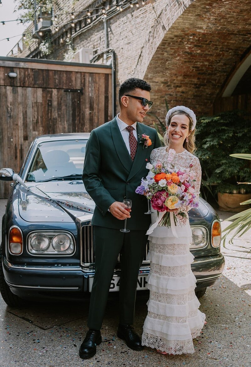 Bride and groom in front of classic car