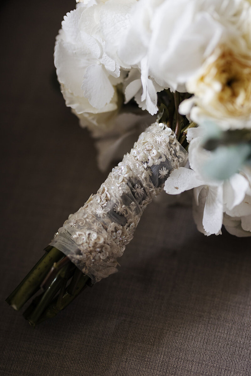 White and cream roses tied with a detailed lace ribbon.