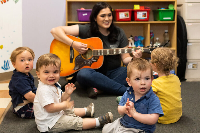 toddlers listening to the guitar being played smiling