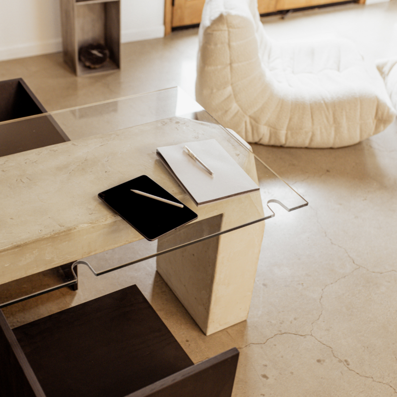 Elegant minimal living space in shades of beige tan white and black  featuring furniture including a desk with folders and pens