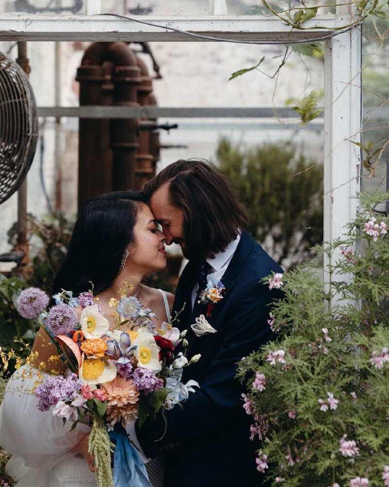 couple-cuddling-with-bouquet-in-greenhouse