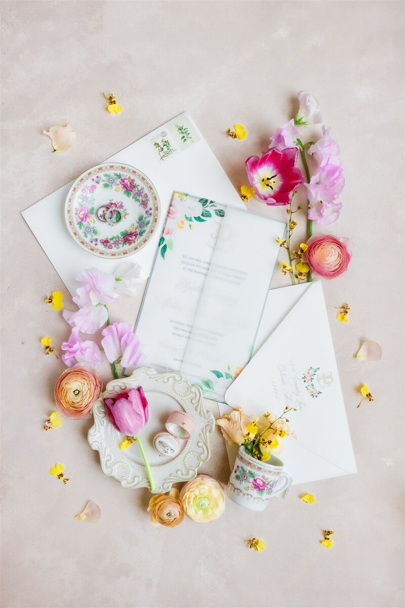Photo of bride's flatlay details with bright and colorful blooms and a gorgeous invitation suite