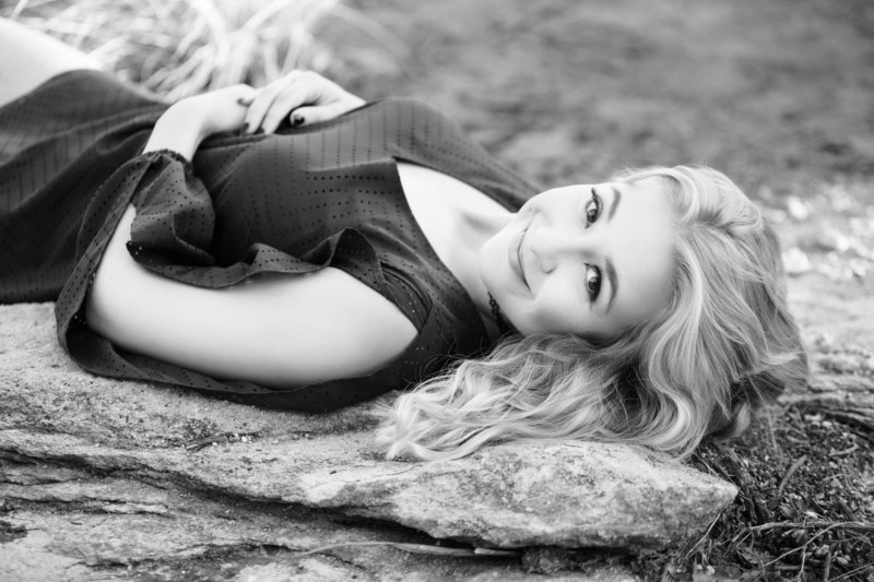 Black and white photo of blonde high school senior laying down by Orlando Graduation Photographer