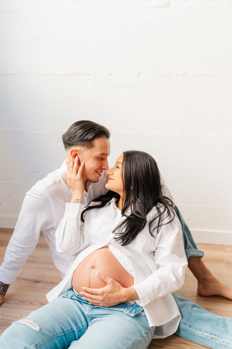 A neutral maternity photo shoot with a couple sharing a moment at a studio in lewiston