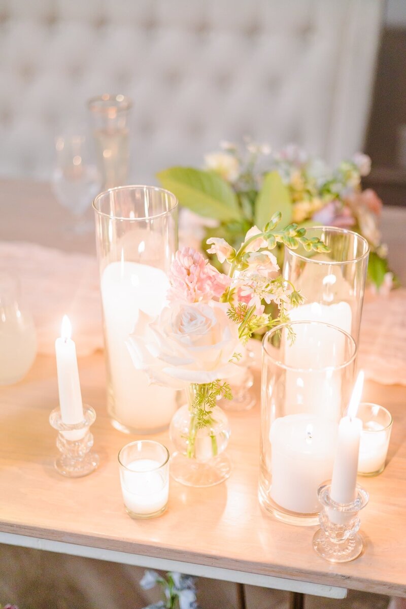 The sweetheart table at this reception is adorned with candles of different heights.