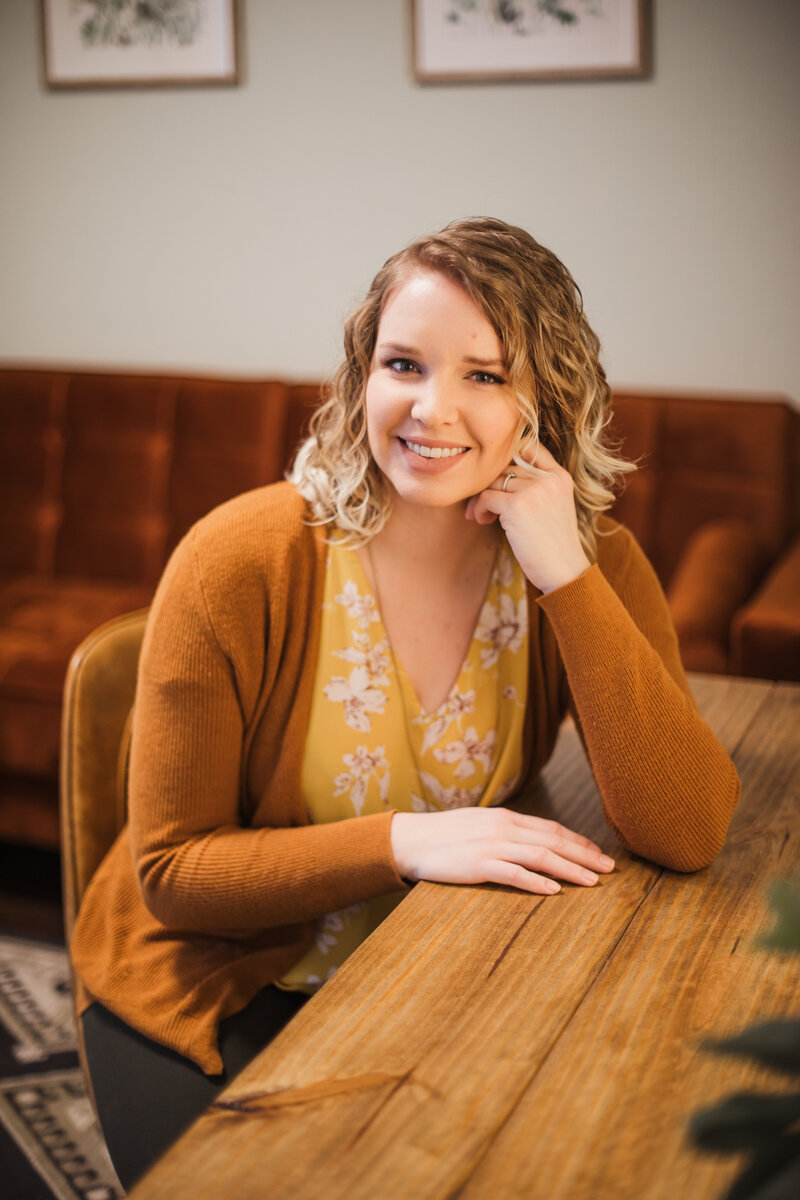 woman sitting at table smiling during Tennessee senior portraits