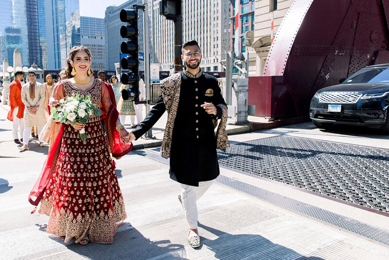 bride and groom walking hand in hand across chicago bridge