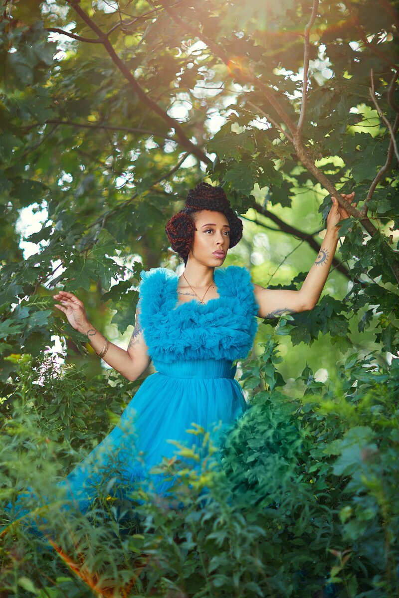 woman in blue dress posing in forest with greenery during golden hour in upstate ny