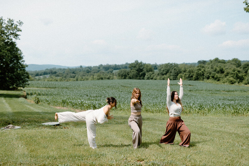 Team members from Alyn Wellness Studio doing yoga poses in a field