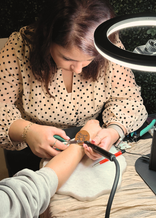 Denisa, owner of Link Art, welding a permanent bracelet at an event.