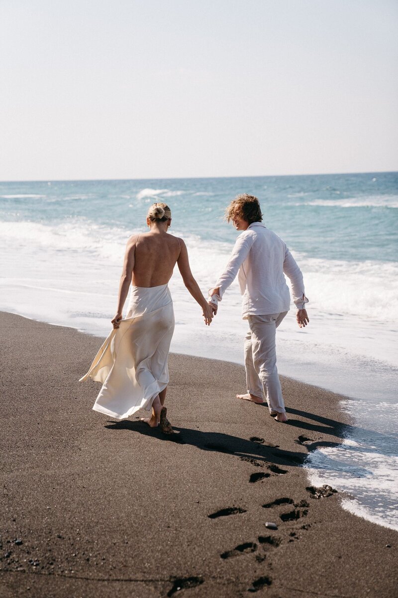 Bride and groom walk on beach