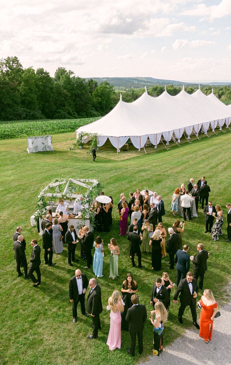 white barn with wedding guests mingling at outdoor wedding venue in upstate new york