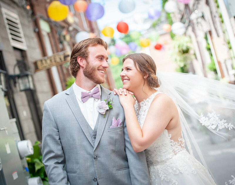 bride and groom look at one another under colorful paper chinese lanterns